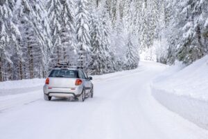 Coche en una carretera con nieve rodeado de arboles cubiertos de nieve