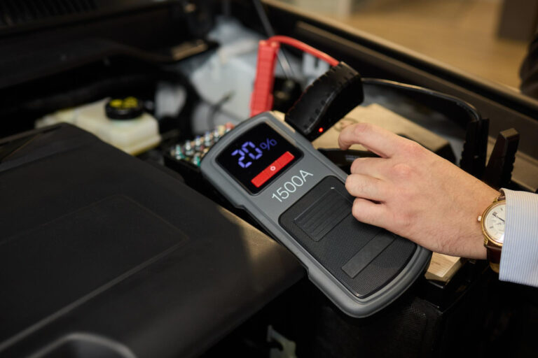 Foto en primer plano de una batería de coche negra conectada con cables de arranque para la reparación o recarga