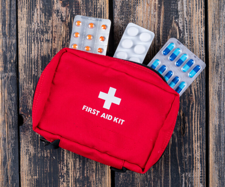 O que levar no teu kit de primeiros socorros para o carro 23 first aid kit with pills top view dark wooden background