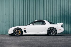 mazda mx 7 con motor rotativo de color blaco sobre fondo industrial verde