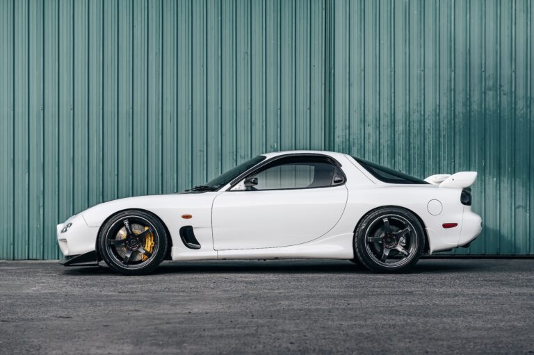 mazda mx 7 con motor rotativo de color blaco sobre fondo industrial verde