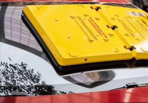 sistema barnacle sobre coche rojo y una mujer con camiseta amarilla intenta quitar