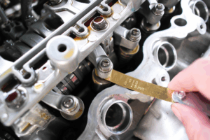 Mecánico inspeccionando el motor de un coche, enfocándose en el sistema PCV para diagnosticar un ralentí inestable.