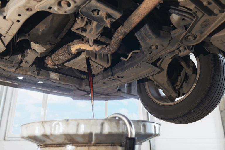 Mecánico examinando la válvula PCV y el sistema de ventilación del cárter de un motor, destacando su importancia en el rendimiento del vehículo.