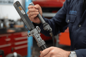 Mecánico utilizando una remachadora en la carrocería de un vehículo en un taller, mostrando la herramienta en acción.