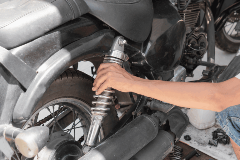 Mécanicien inspectant la coupelle d’amortisseur d’un véhicule pour identifier l’origine d’un bruit.