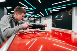 Technicien utilisant une brosse rotative pour le detailing d’une voiture dans un atelier professionnel.