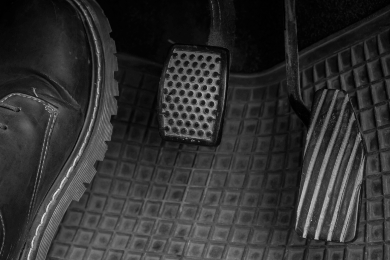 Diagnóstico de avarias: O que significa o pedal da embraiagem trepidante? 8 Mecânico a inspecionar o sistema de embraiagem de um automóvel, focando-se no pedal e nos componentes associados a vibrações.