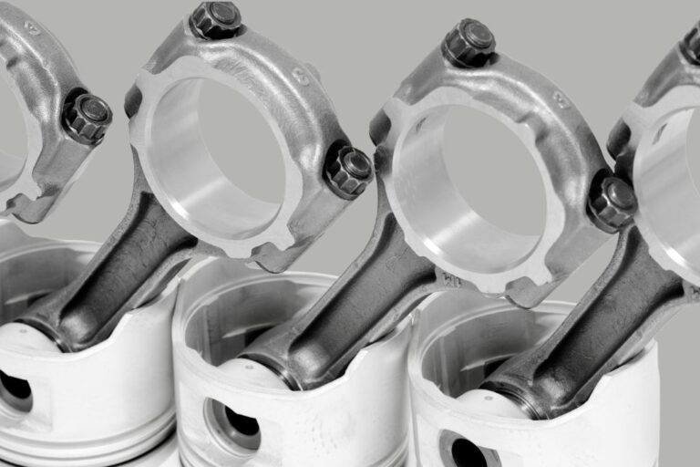 Biela de motor destacada sobre uma bancada de oficina, ilustrando o diagnóstico de avarias e manutenção.