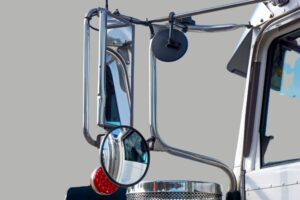 Técnico de oficina ajustando espelhos e acessórios de um veículo para eliminar pontos cegos.