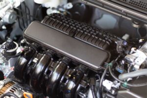 Motor de veículo aberto numa oficina, com destaque para a centralina e os seus componentes, ilustrando a reprogramação.