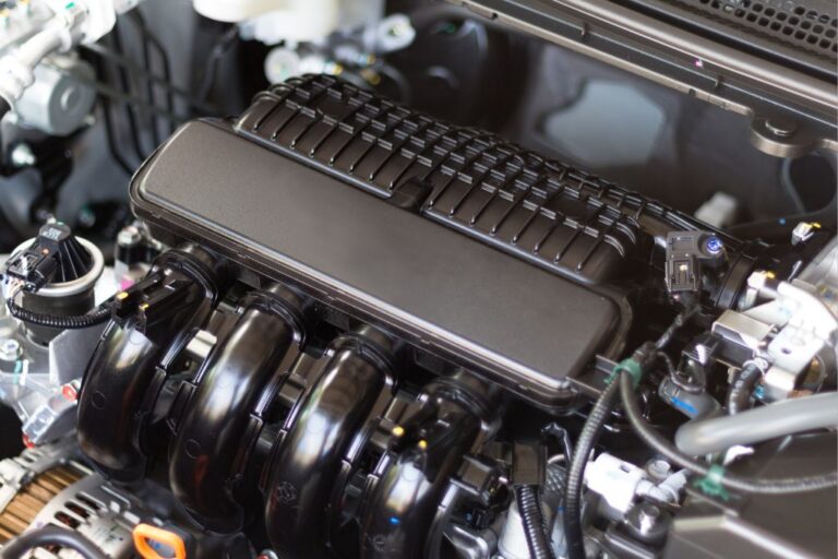 Motor de veículo aberto numa oficina, com destaque para a centralina e os seus componentes, ilustrando a reprogramação.