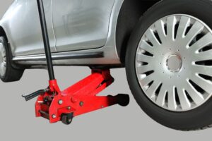 Macaco hidráulico numa oficina automóvel, pronto a levantar um veículo, ilustrando diferentes modelos disponíveis.