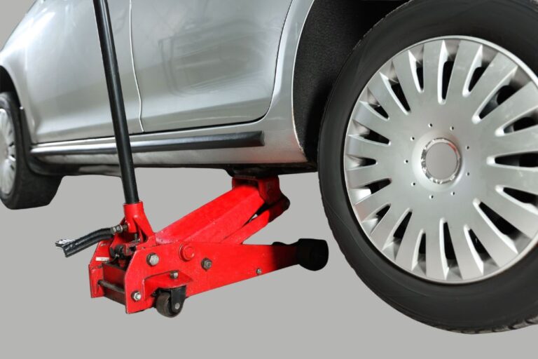 Macaco hidráulico numa oficina automóvel, pronto a levantar um veículo, ilustrando diferentes modelos disponíveis.