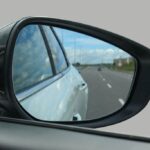 Técnico de oficina a verificar retrovisores de um veículo, destacando a adaptação à nova legislação.