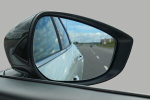 Técnico de oficina a verificar retrovisores de um veículo, destacando a adaptação à nova legislação.