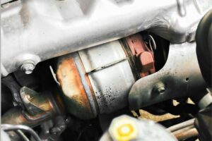 Catalisador automóvel sobre uma bancada de oficina, ilustrando análise de preço e substituição.