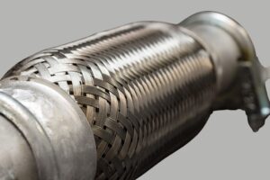 Mecánico evaluando un flexible de escape para decidir entre su reparación o sustitución según la rentabilidad.