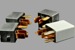 Technicien automobile vérifiant un relais statique dans le système électrique d’un véhicule moderne.