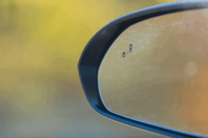 Technicien automobile testant un capteur d’angle mort sur un véhicule en atelier.