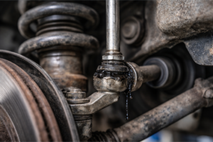 Técnico del taller inspeccionando bieletas de suspensión de un vehículo para detectar fallos.