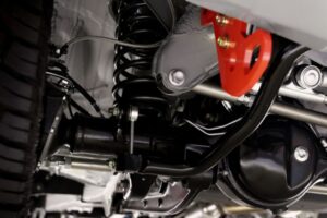 Technicien inspectant la suspension d’un véhicule pour diagnostiquer un bruit provenant de la rotule ou du silentbloc.