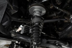 Técnico a inspecionar molas, amortecedores e batentes de suspensão de um veículo numa bancada de oficina.