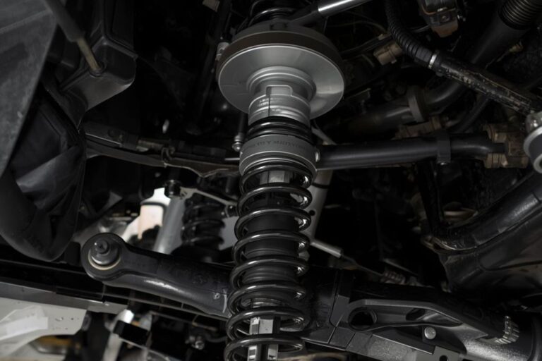 Técnico a inspecionar molas, amortecedores e batentes de suspensão de um veículo numa bancada de oficina.