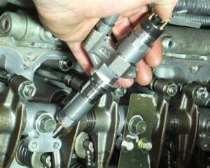 Mecánico utilizando un extractor de inyectores neumático para retirar un inyector del motor.