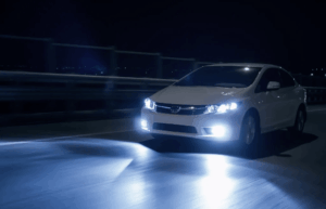 Mecánico inspeccionando relés, módulos y cableado del circuito de luces antiniebla de un vehículo.