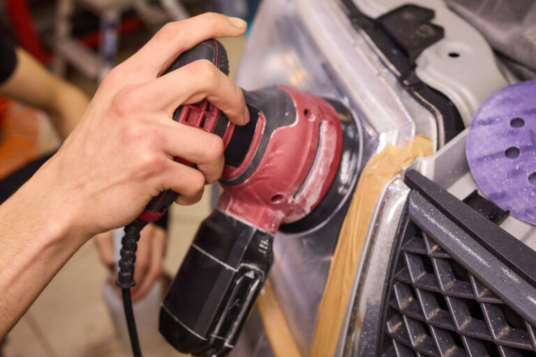 persona que utiliza una maquina para pulir la iluminacion de automoviles en un faro de automovil