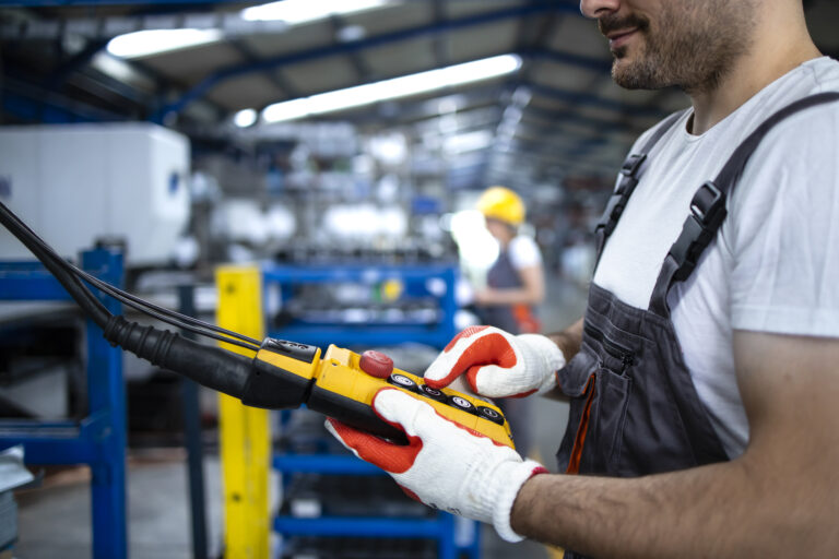 Guía de seguros de responsabilidad civil para talleres y recambistas 4 factory worker wearing uniform hardhat operating industrial machine with push button joystick production hall