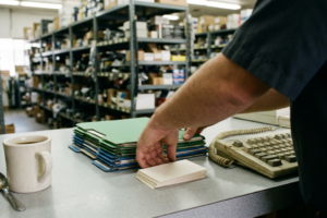 Profesional atendiendo a un cliente en el mostrador de recambios, en un entorno comercial orientado al servicio, la confianza y la fidelización.