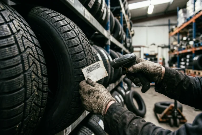 Professionnel en train de gérer un stock saisonnier de pneus hiver pour flottes, dans un environnement logistique et technique.