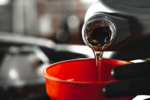 Profesional de automoción revisando especificaciones técnicas de aceite motor y normativas actualizadas en un taller o entorno técnico.