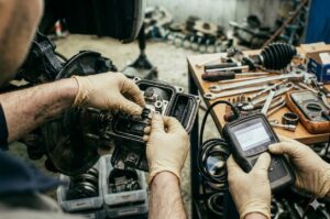 Technicien automobile en train d’effectuer l’entretien d’un frein à main électronique à l’aide d’un outil de diagnostic, dans un atelier professionnel.
