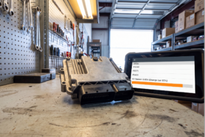Unidad de control del motor ECU desmontada sobre un banco de trabajo junto a un escáner que muestra códigos de avería DTC P0300, P0171 y P0420.
