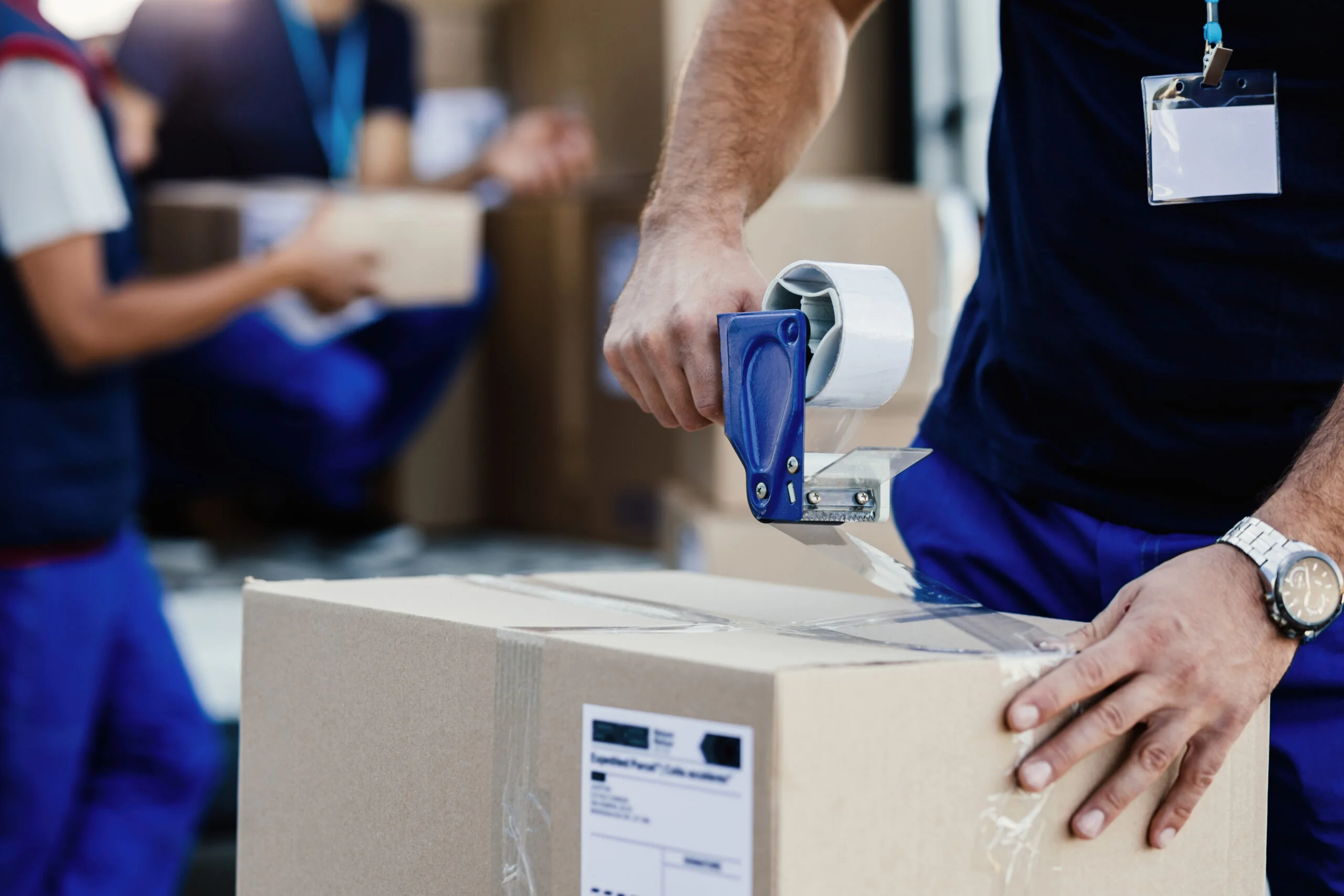 closeup-delivery-man-closing-carboard-box-with-tape-while-preparing-packages-shipment-scaled.jpg