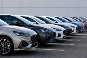 Fila de coches modernos de varios colores aparcados en línea frente a un edificio