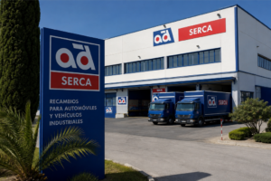 Fachada de la nave industrial de AD Serca con cartel corporativo y dos camiones de reparto aparcados.
