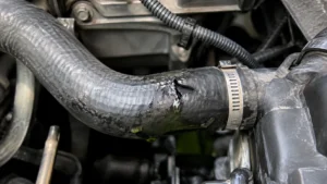 Radiador novo sobre uma mesa de trabalho ao lado de um carro com o radiador antigo instalado e um mecânico a utilizar um tablet.