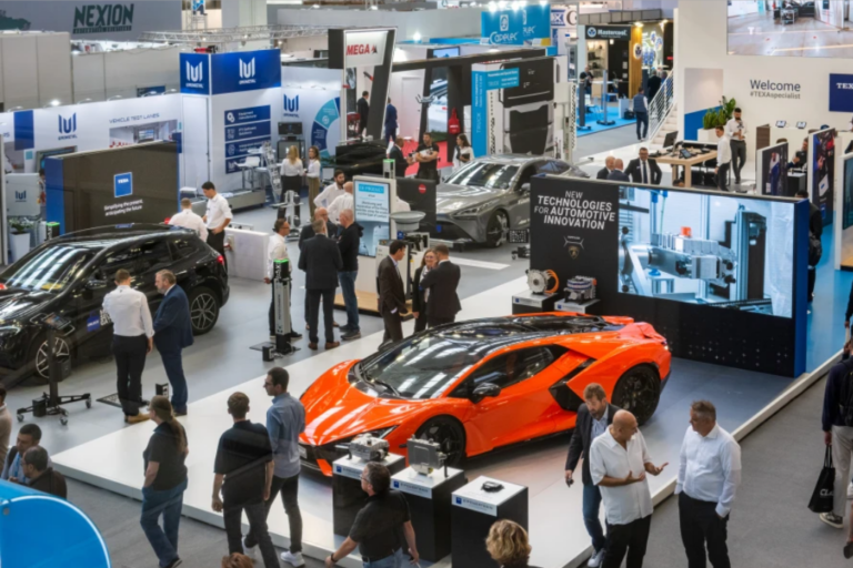 Stand de feria sobre innovación automotriz con un deportivo naranja expuesto y profesionales del sector.