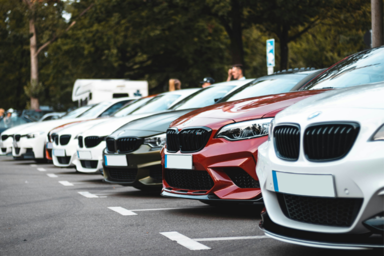 Línea de coches BMW aparcados en un estacionamiento exterior, destacando modelos en color blanco, rojo y verde
