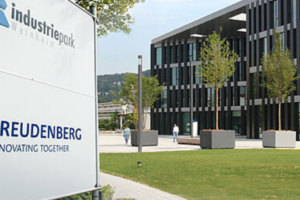 Cartel del parque industrial de Freudenberg frente a un moderno edificio corporativo