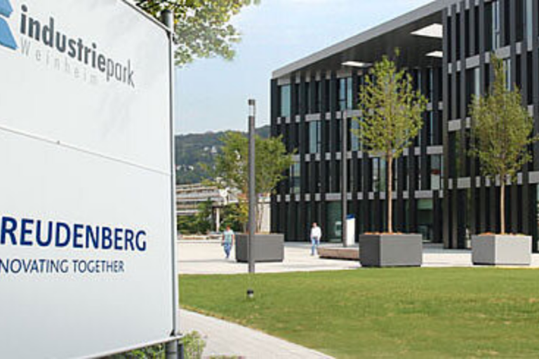 Cartel del parque industrial de Freudenberg frente a un moderno edificio corporativo