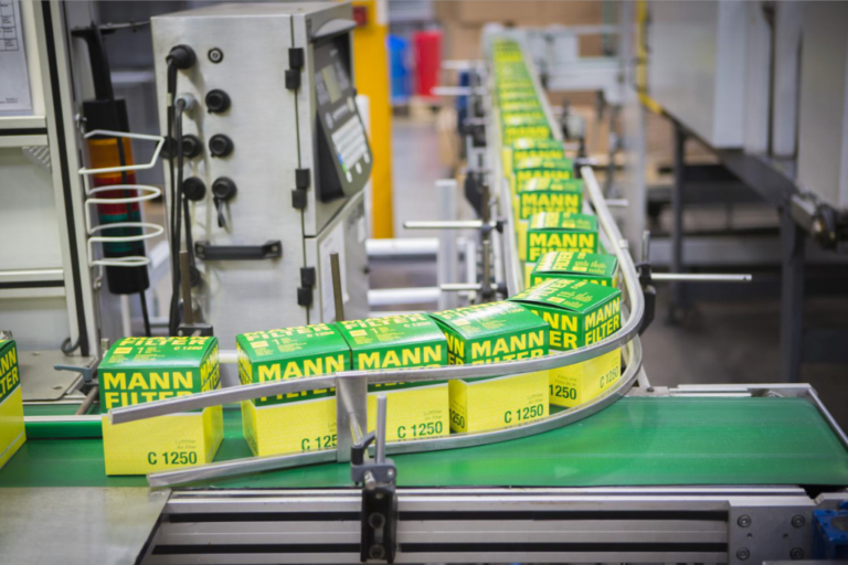 Cajas de filtros de aire Mann Filter C 1250 avanzandando por una cinta transportadora automatizada en fábrica.