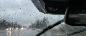 Técnico com luvas a segurar um tablet a procurar a peça de substituição para um farolim traseiro partido de um carro cinzento.