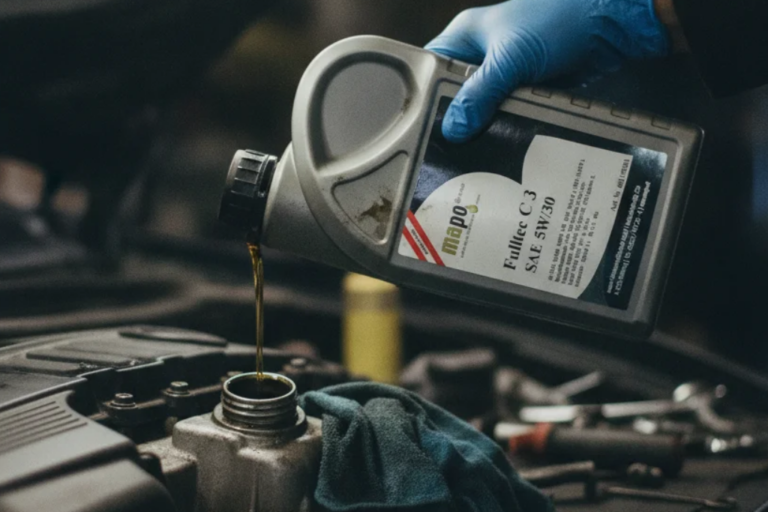 Mecânico com luva azul a verter óleo de motor sintético SAE 5W-30 de um frasco prateado no bocal de enchimento do motor.