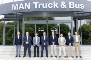 Grupo de ocho directivos y ejecutivos posando frente a la entrada de las instalaciones de MAN Truck & Bus.